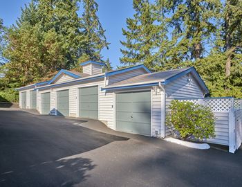 Outdoor garages with paved pathway to entrance and trees behind.at Edmonds Gateway, Edmonds Washington